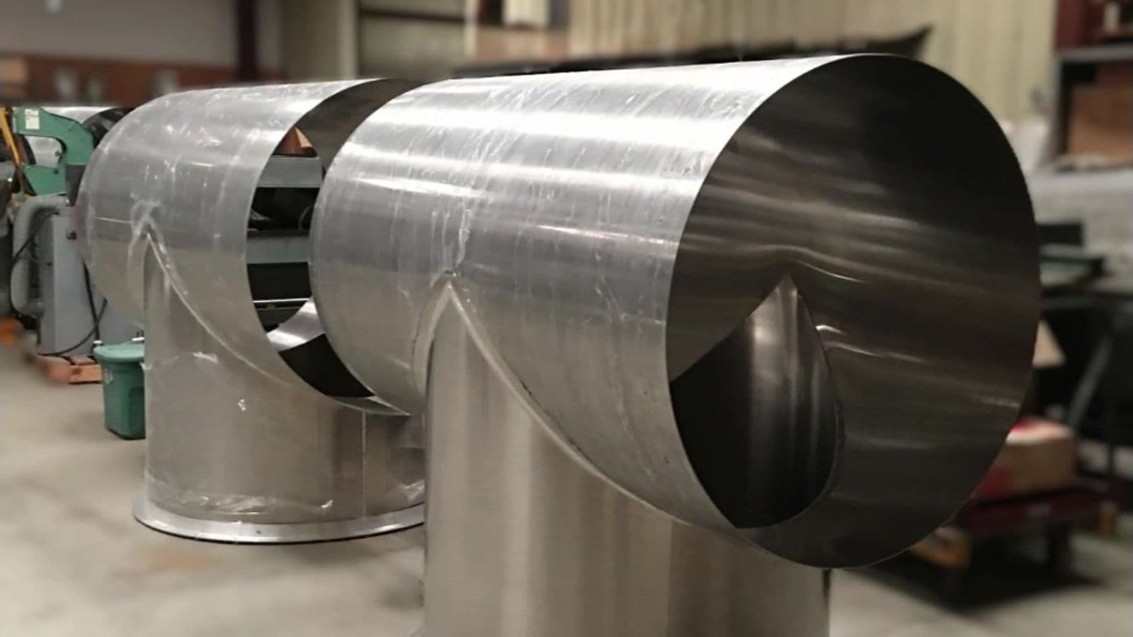 Row of large-diameter stainless steel 90-degree duct elbows lined up on the Hudson Sheet Metal shop floor