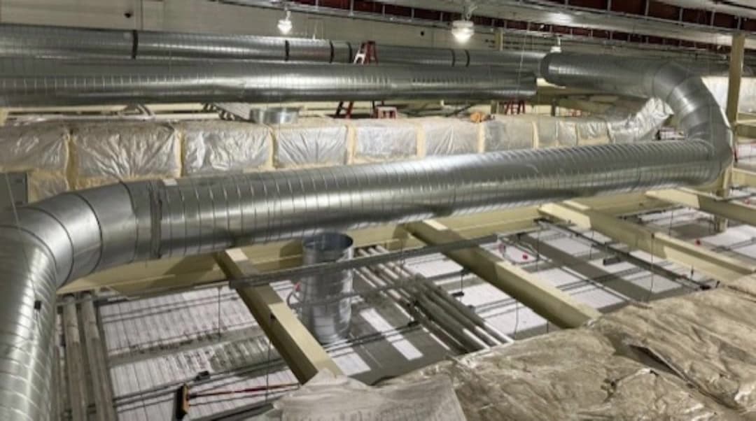 Spiral galvanized ductwork installed along a commercial building ceiling during construction